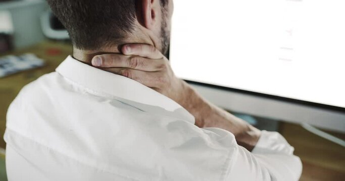 Businessman suffering from neck pain and tense muscles while messaging to relieve tension while working on a computer. Professional with bad posture and a headache feeling discomfort from long hours
