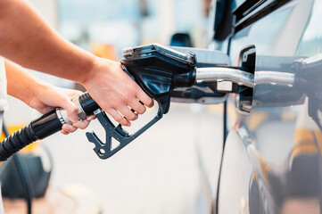 Closeup of woman pumping gasoline fuel in car at gas station. Petrol or gasoline being pumped into a motor. Transport concept - obrazy, fototapety, plakaty