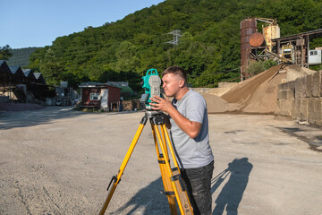 Portrait of a young man next to a total station in the open air. A surveyor working with a total...