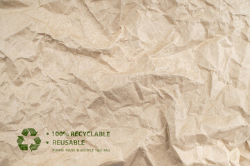 Recycled brown creased paper background from a paper packing with green recycling symbol. Ecology environmental safety concept