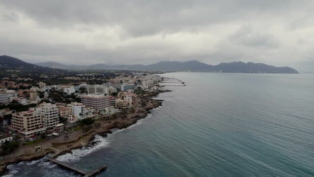 Aerial drone shot of the shore of Cala Millor, Mallorca, Balears Islands, Spain. the town of Cala Millor and the mountains at dusk. along the sandy Cala Millor coastline with luxury hotels.
