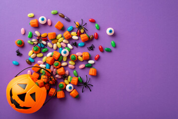 Halloween concept. Top view photo of pumpkin basket with candies eyes and spiders on isolated...