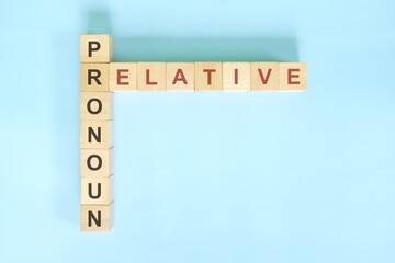 Relative pronoun concept in English grammar education. Wooden block crossword puzzle flat lay in blue background.