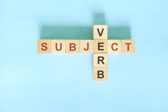 Subject verb agreement concept in English grammar education. Wooden block crossword puzzle flat lay in blue background.