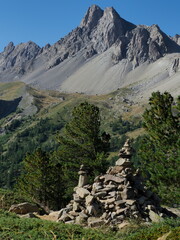 Fototapeta na wymiar cairn sur fond de vallée de la clarée dans les hautes alpes, avec ligne de crête et ciel bleu