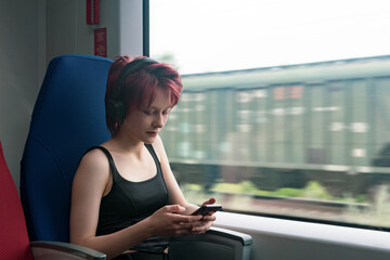 young woman rides on a train immersed in a smartphone