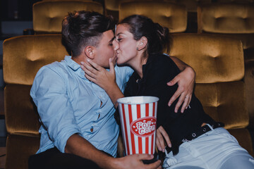 Young couple hugging and kissing while watching a movie in a movie theater.