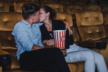 Young couple hugging and kissing while watching a movie in a movie theater.