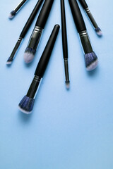 Creative concept beauty fashion photo of cosmetic product make up brushes kit on blue background.