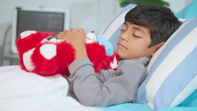 unhealthy child with teddy bear sleeping on bed at hospital ward - concept of medical treatment, health care and illness.