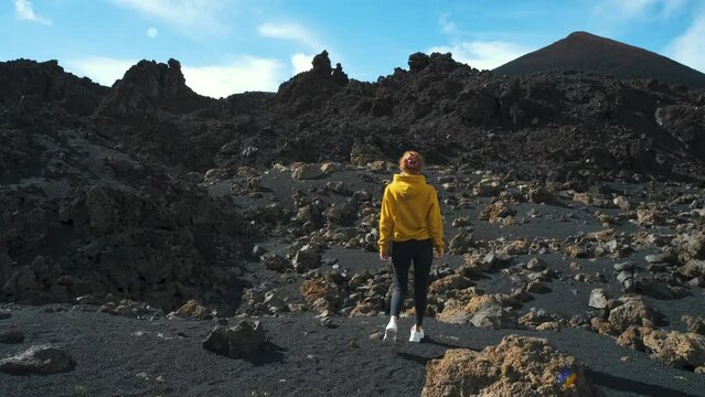 Woman traveler walks through the lava field around Chinyero volcano in the Teide national park on the island of Tenerife. Go Everywhere. Surface of another planet. Slow motion shot
