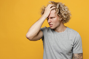 Young mistaken confused caucasian man 20s he wear grey t-shirt put hand on face facepalm epic fail mistaken omg gesture isolated on plain yellow backround studio portrait. People lifestyle concept