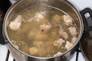 Meat broth during cooking in pot on a stove top