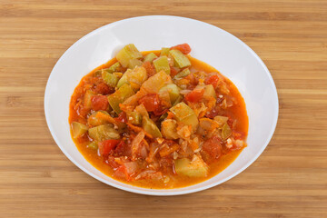 Marrows stewed with other vegetables in bowl on wooden surface