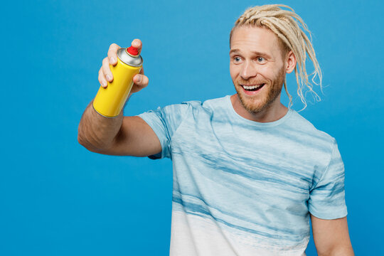 Young cool happy blond man with dreadlocks 20s he wear white t-shirt hold in hand spray aerosol paint bottle isolated on plain pastel light blue background studio portrait People lifestyle concept.