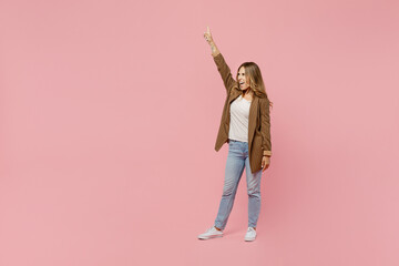 Full body young excited fun cool successful employee business woman 30s she wear casual brown classic jacket point index finger up raise up hand isolated on plain pastel light pink background studio.