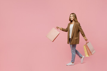Fototapeta premium Full body young successful employee business woman 30s she wear casual brown classic jacket hold package bags with purchases after shopping go isolated on plain pastel light pink background studio.