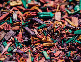 Textured background of decorative colored sawdust for finishing flower beds. Green, burgundy, yellow, red and purple sawdust. The texture of small colored wood chips.