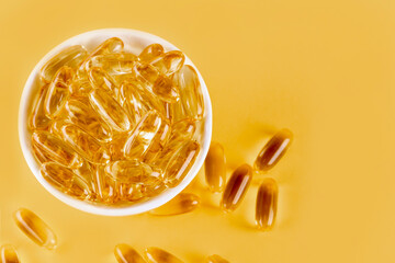Omega 3 capsules lying on yellow background. Fish oil in pills. Health support and treatment. Biologically active additives. Selective focus.