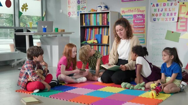 Female teacher reading story to group of elementary pupils in school classroom