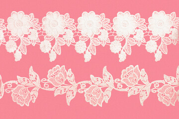 White laces with flowers and leaves on pink background isolated horizontally