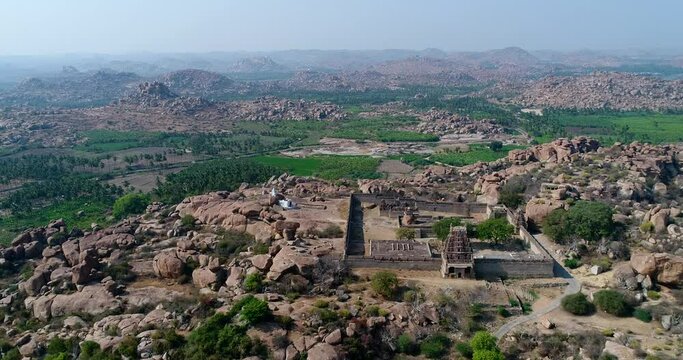 Aerial shot of rocky landscape with bouldery hills, hindu temple on top