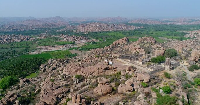 Aerial shot of rocky landscape with bouldery hills, hindu temple on top