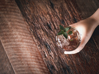 top view over person holding a glass of mojito virgin with aged wood table space 
