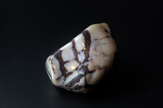 Zebra jasper chalcedony tumbled stone macro isolated on black background
