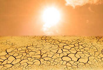 Dryness concept weathered texture of arid cracked ground with sunrise view and yellow sky background