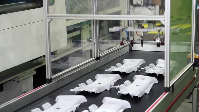 Robotic Arm In Automotive Industry. Pick And Place Robot Placing New Plastic Parts On The Conveyor Belt. Automated Production Line For Automobile Parts Manufacturing. 