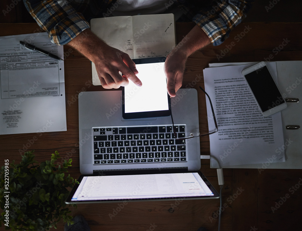 Poster Laptop and tablet in the hands of a man working late at night in the office from above. Deadline and overtime at a desk with technology and paper work. Sending an email reading or typing a report