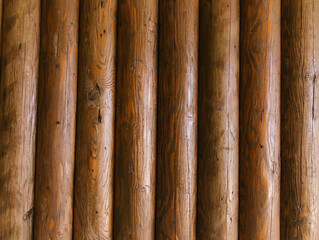 Wooden logs walls of the house. Texture of brown logs. Rustic background. Vertically arranged boards.