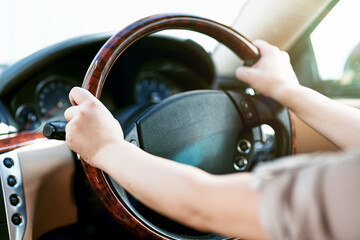Hands of a driver on a steering wheel in a car for travel, driving or taking a roadtrip. Take a...