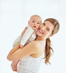 Portrait of a happy young mother hugging her cute baby boy at home, bonding and enjoying...