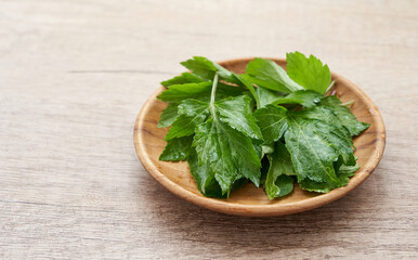 heap of white mugwort or wormwood Artemisia lactiflora in wooden plate on wood table background. superfood white mugwort leave background      
