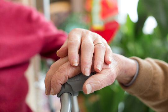 hands of ederly couple holding a cane
