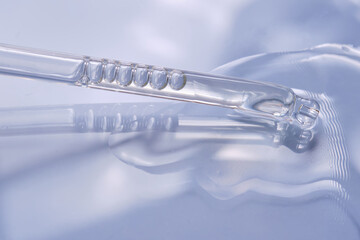 Dropper with serum or cosmetic oil on a blue background.