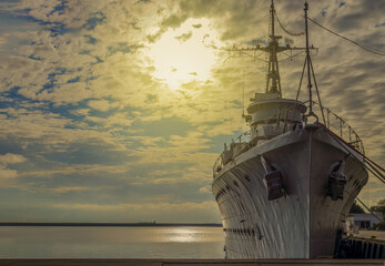 Historical warship standing in the port against the backdrop of the rising sun in Gdynia, Poland