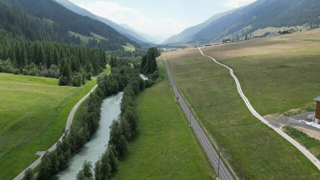 Aerial point of view on valley in Switzerland. Drone flies above the empty railway and mountain river. Transport logistic system. Swiss railway