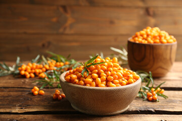 Fresh ripe sea buckthorn in bowl on wooden table. Space for text