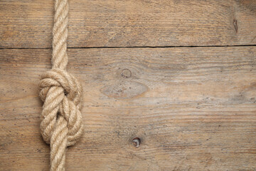 Fototapeta na wymiar Top view of linen rope with knot on wooden background, space for text. Unity concept