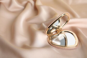 Stylish heart shaped cosmetic pocket mirror on rose gold fabric, space for text