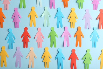 Many different paper human figures on light blue background, flat lay. Diversity and inclusion...