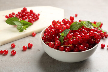Delicious red currants and mint in bowl on light grey table