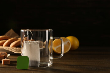 Tea bag in empty glass cup on dark wooden table. Space for text