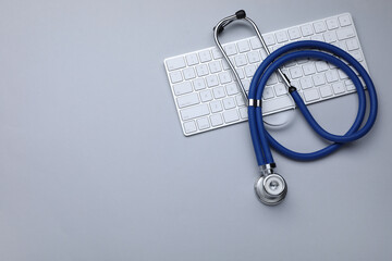 Keyboard and stethoscope on white background, flat lay. Space for text - obrazy, fototapety, plakaty