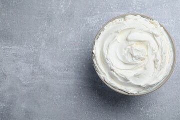 Bowl of tasty cream cheese on light grey table, top view. Space for text