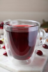 Glass cup of fresh dogwood tea on white marble board