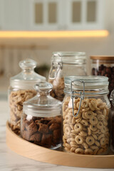 Glass containers with different breakfast cereals on white marble table in kitchen